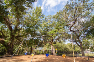 A swingset shaded by trees